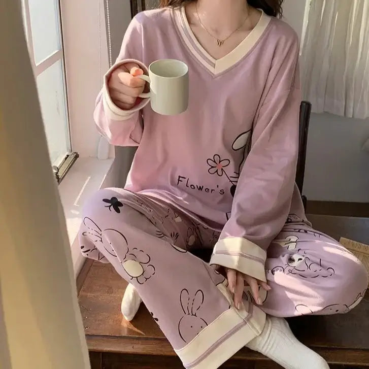 Person wearing pink pajamas with floral design, holding a mug and sitting by a sunny window.