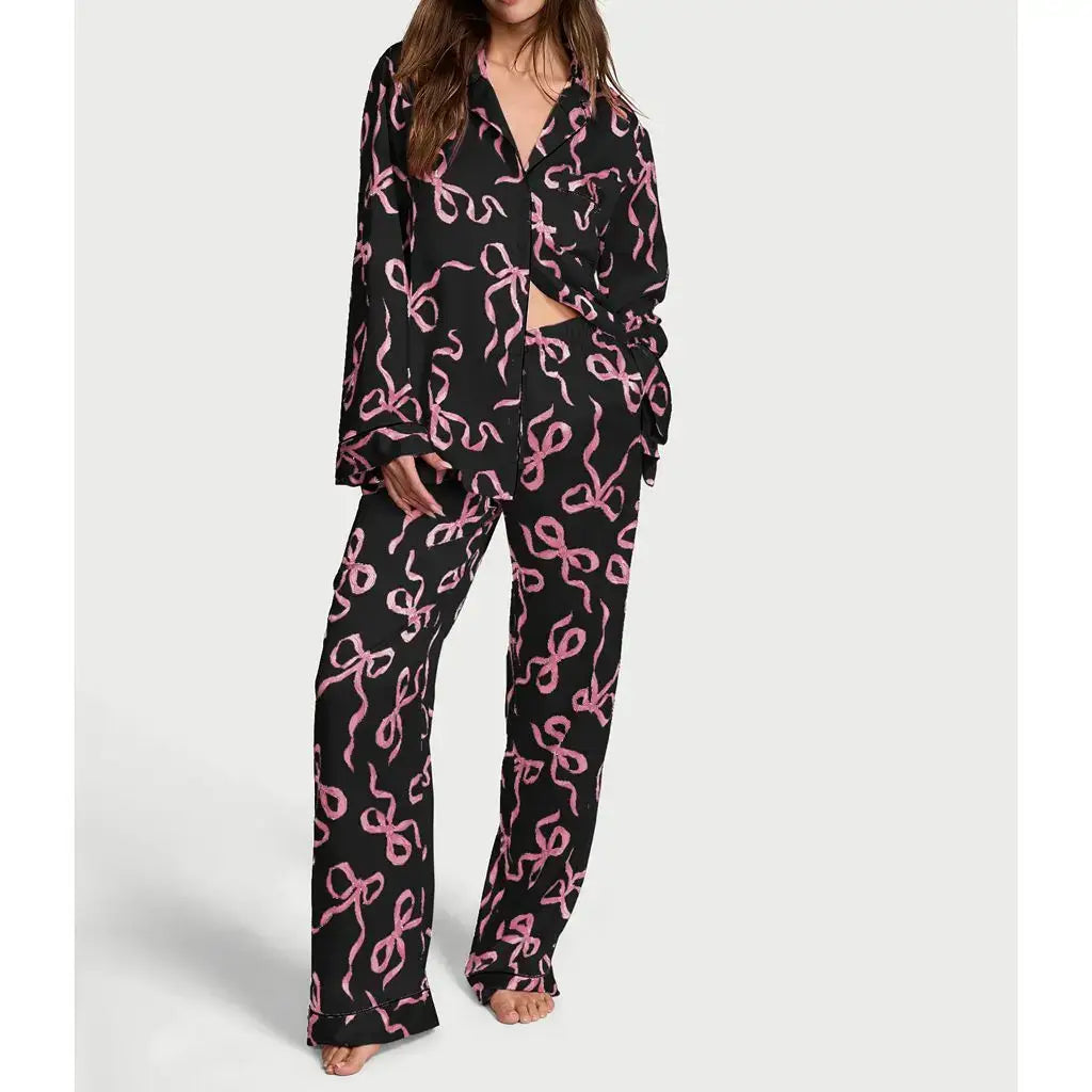 Black satin pajamas with pink pattern, made from organic cotton. Features relaxed fit and breathable material for comfort.