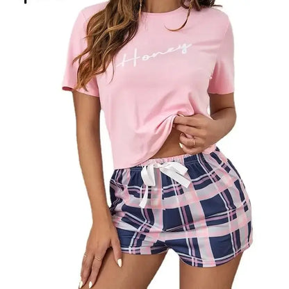 Ladies pajama set in organic cotton, featuring a pink top and plaid shorts. Relaxed fit with breathable material for comfort.