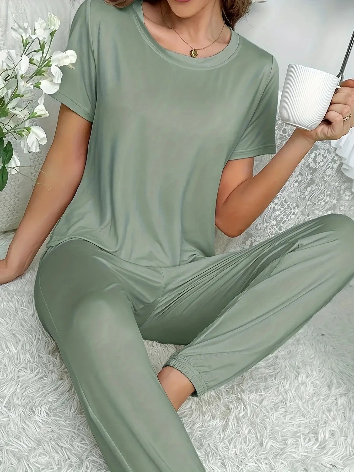 Woman in organic cotton sleepwear set, relaxed fit, holding a mug. The material is breathable and comfortable for nightly comfort.